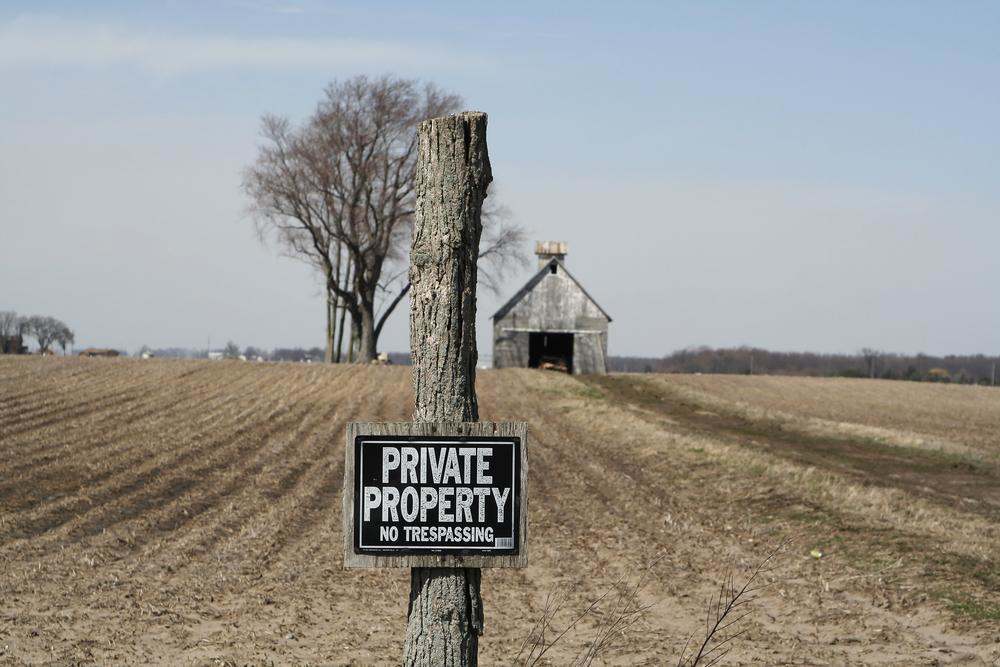 A private property sign posted in front of an abandoned rural property