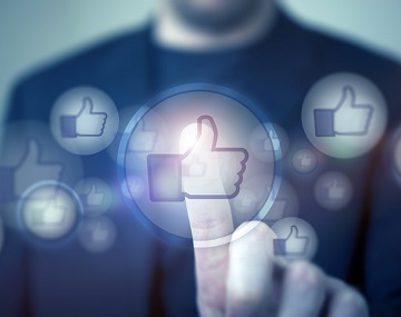 Stock photograph of a person in a suit with Facebook likes in bubbles floating past. The person is raising their index finger to touch one of the bubbles.