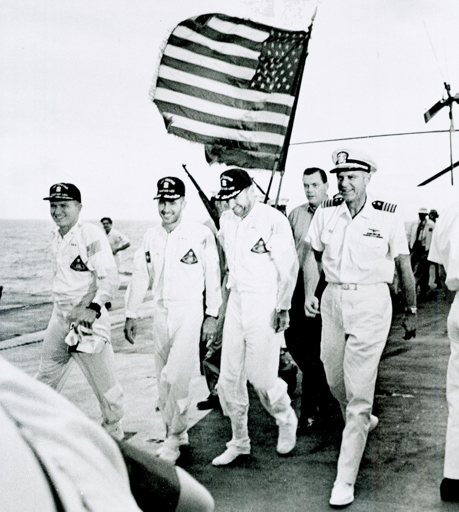 Apollo 8 astronauts and commanding officer of the recovery ship USS <em>Yorktown</em> walk the red carpet of the flight deck after splashdown recovery in the Pacific Ocean. 