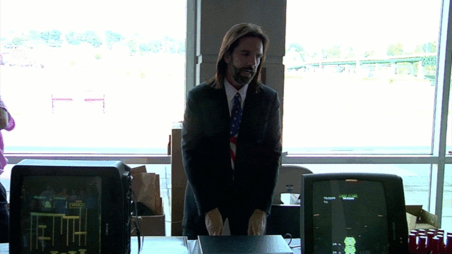 Mitchell stands behind footage of his claimed 1.06 million point <em>Donkey Kong</em> game at a 2010 press conference (click for slow motion animation that seems to show a MAME screen transition).