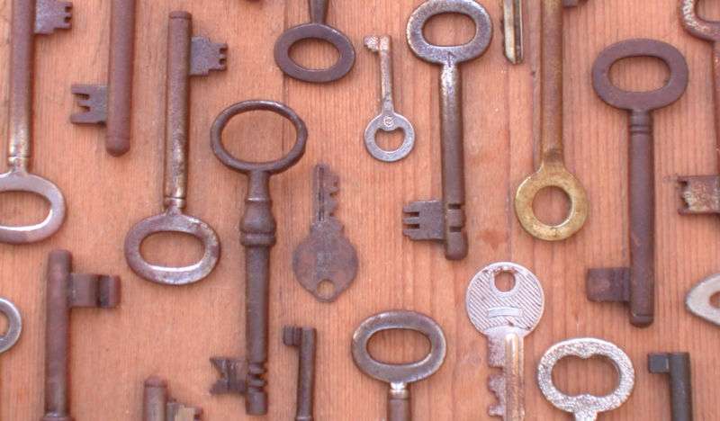 A large number of keys against a light-colored wooden background.