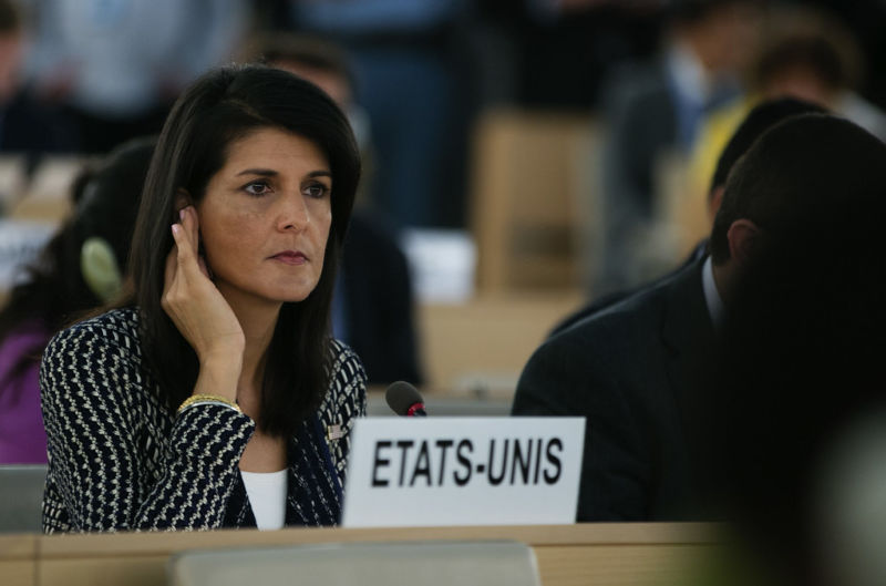 A serious woman listens intently to an earpiece.