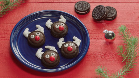 Reindeer oreo cookies on a blue plate with 3 oreos on the red table