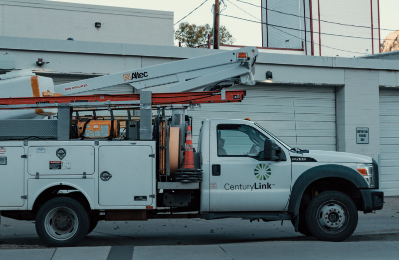 A white truck with a CenturyLink logo is parked next to a building.