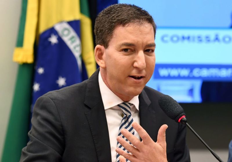 Glenn Greenwald speaking and gesturing with his hand at a government hearing in Brazil.