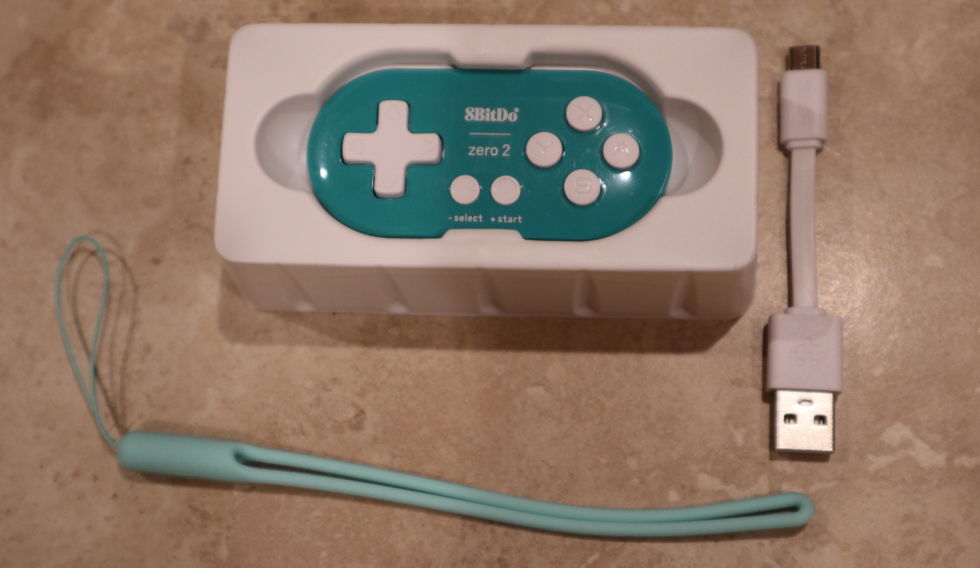 The 8BitDo Zero 2 comes with everything seen here: a nylon carrying strap and a micro-USB cable for charging and updating controller firmware. (The controller does <em>not</em> work in wired mode, only Bluetooth.)