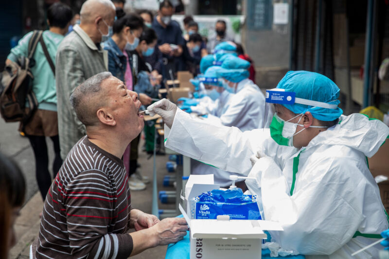 Medical workers take swab samples from residents (L) to be tested for the COVID-19 coronavirus, in a street in Wuhan in China's central Hubei province on May 15, 2020. - Authorities in the pandemic ground zero of Wuhan have ordered mass COVID-19 testing for all 11 million residents after a new cluster of cases emerged over the weekend.