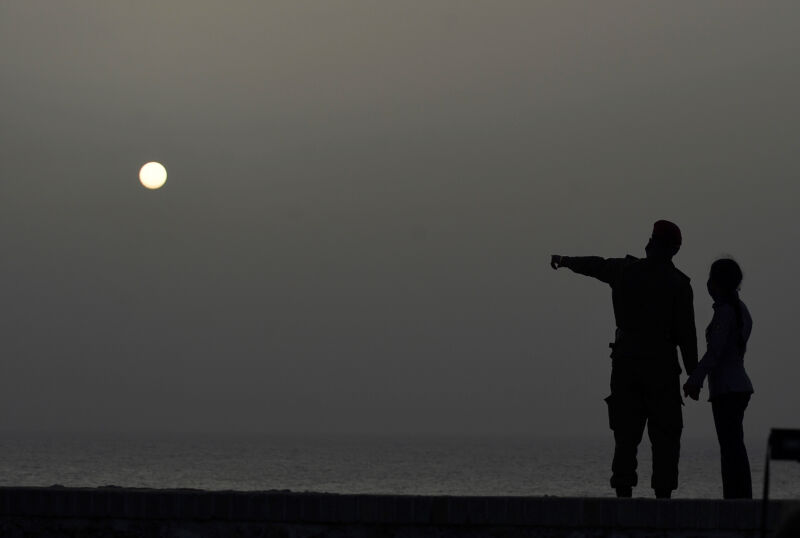 A couple looks at the sea as a vast cloud of Sahara dust is blanketing the city of Havana on June 24, 2020. (Photo by YAMIL LAGE/AFP via Getty Images)