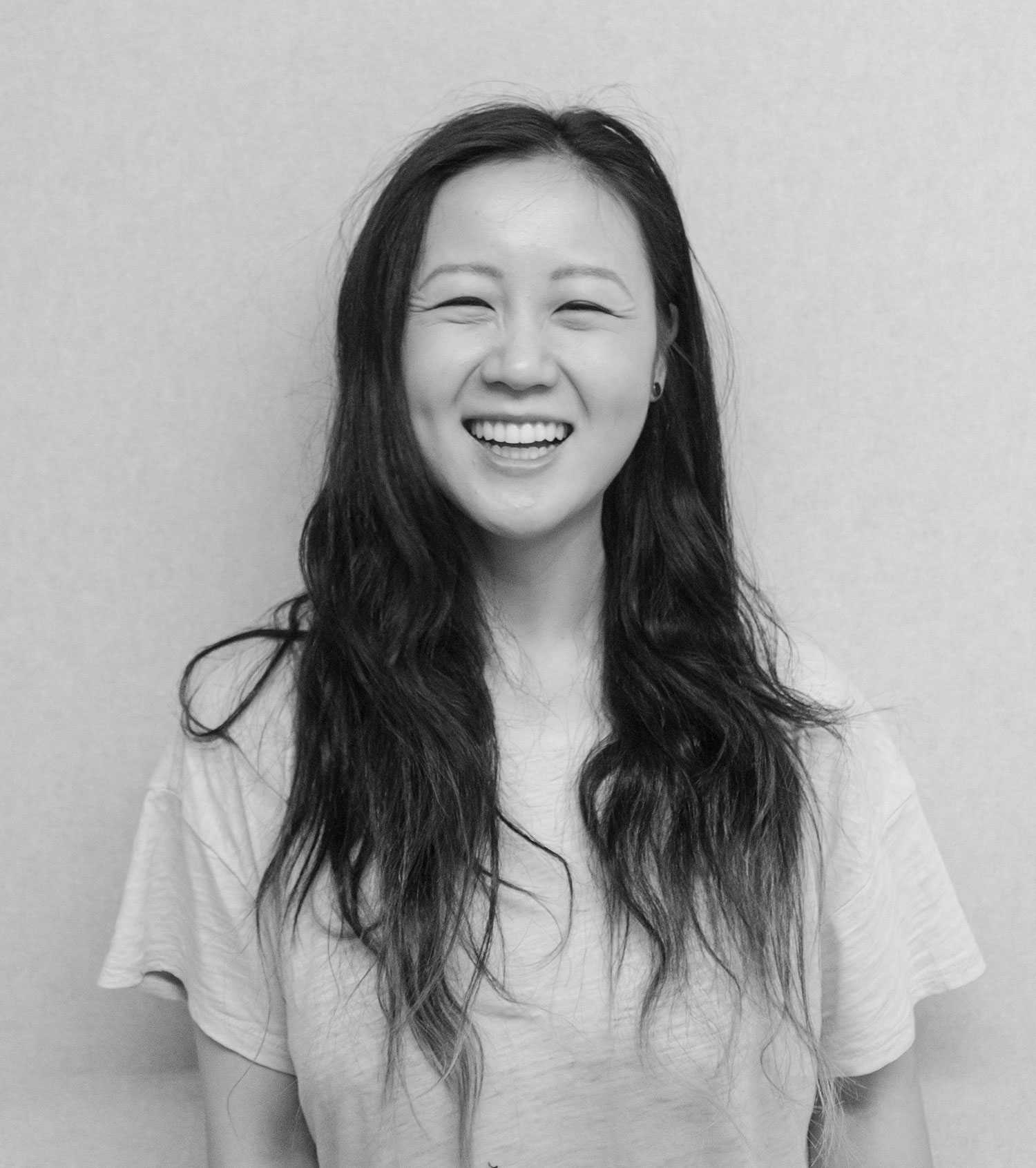 Young woman, with long dark hair, wearing a white t-shirt, smiling