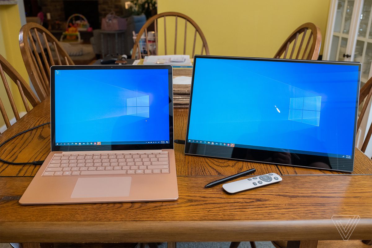 The Ananta portable display connected to a Surface Laptop 3 on a wood table.