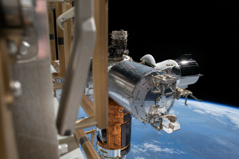 SpaceX's Crew Dragon (center right), the Japanese HTV resupply ship (center bottom), and Europe's Columbus laboratory module appear in this photo taken during a spacewalk conducted by Bob Behnken and Chris Cassidy.