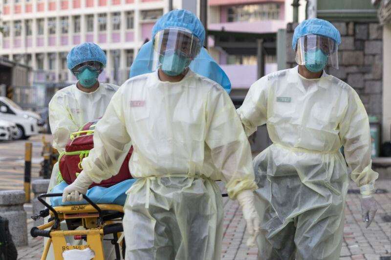 People in protective gear pull a gurney.