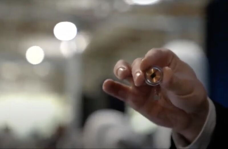 Image of a hand holding a small metal disk.