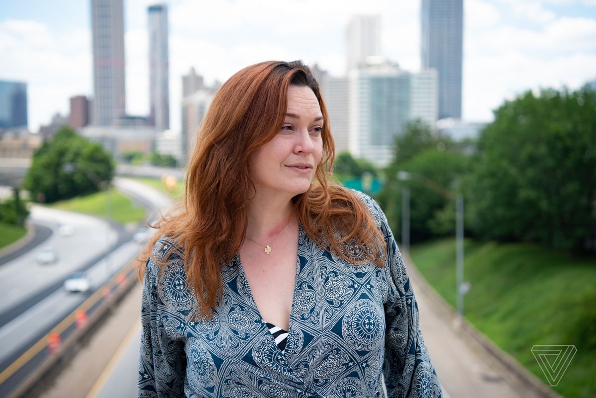 Sarah Owings stands outside for a portrait on an overpass with a highway in the background.