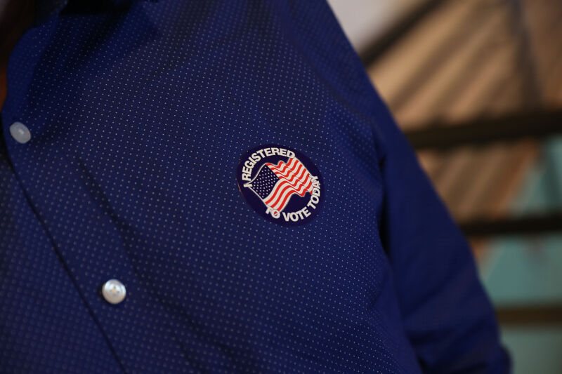 Close-up photograph of a man's shirt with a sticker attached.