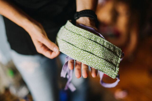 Caucasian young woman's hands holding handmade protective mask. Close up.