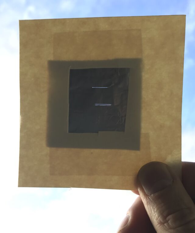 Horizontal slits in aluminum foil made with razor blades. The upper slit is from a single blade, while the lower is from two blades taped together.