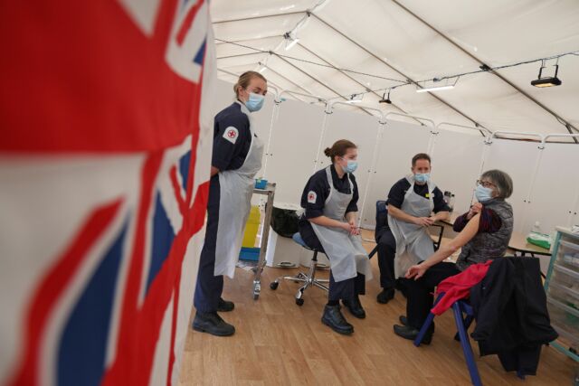 A patient prepares to receive an injection of the Oxford/AstraZeneca COVID-19 vaccine by Royal Navy medics at a vaccination center set up at Bath racecourse in Bath, southwest England.