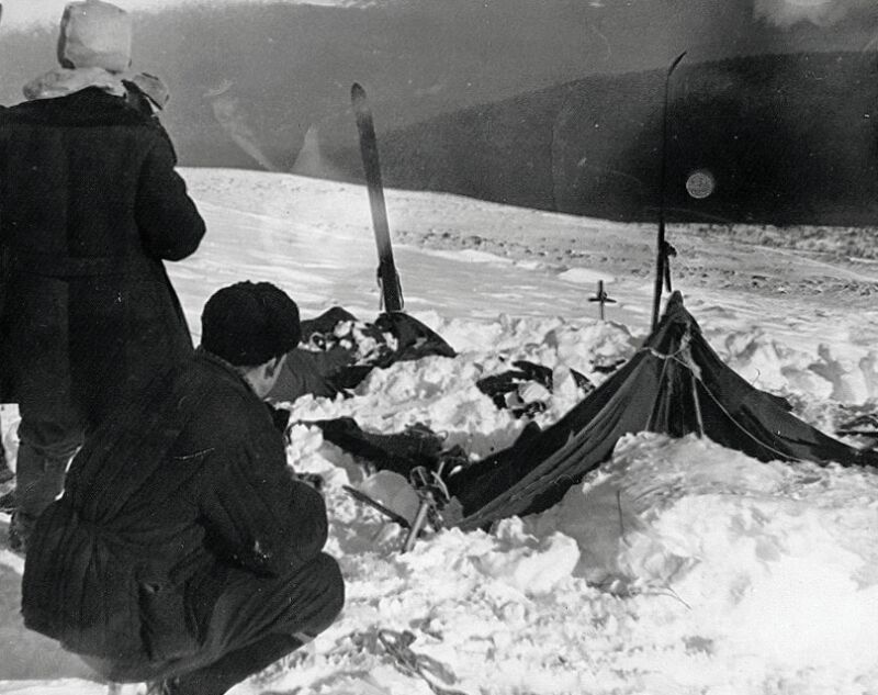 Heavily bundled explorers examine an abandoned campsite.