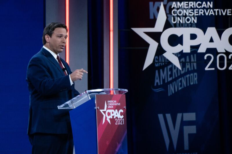 Florida Gov. Ron DeSantis speaking at a podium near a sign that says, 