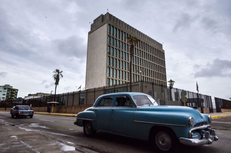 1950s cars driving past a Brutalist, multistory concrete building is peak Cuba.