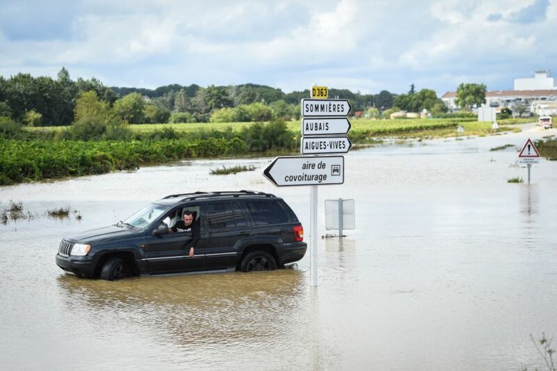 Image of a car stuck near a flooded road.