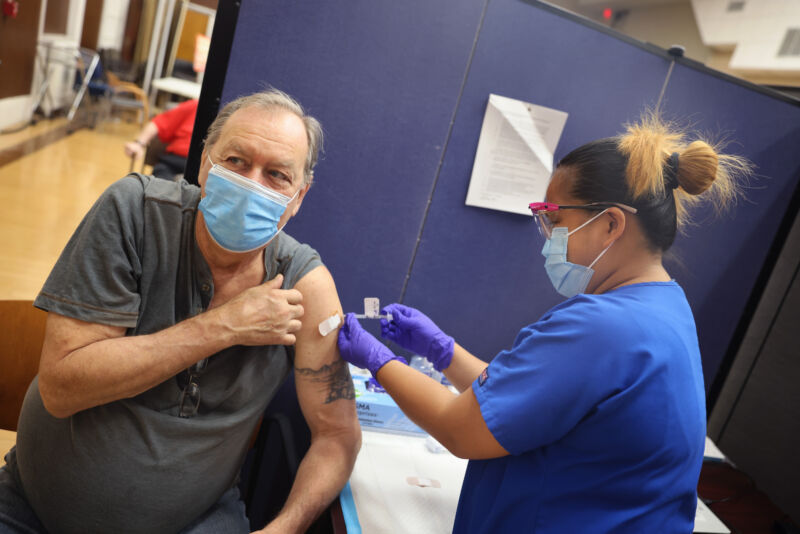 A health worker administers a COVID-19 booster vaccine and an influenza vaccine to an Army veteran at the Edward Hines Jr. VA Hospital on September 24, 2021, in Hines, Illinois. 