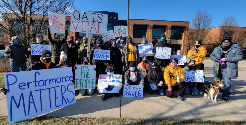 Warmly dressed and mostly masked workers hold protest signs.