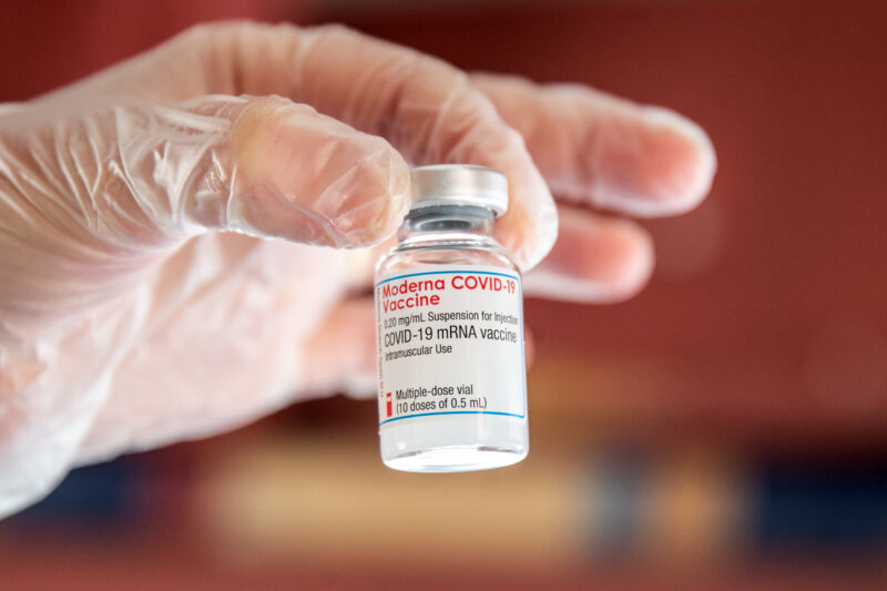 Extreme close-up photo of a gloved hand holding a tiny jar.