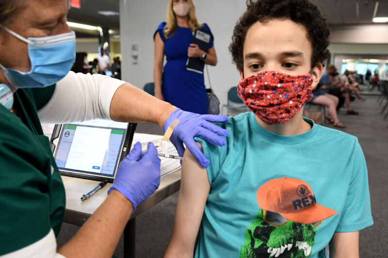 A nurse gives a 16-year-old a COVID-19 vaccine. 