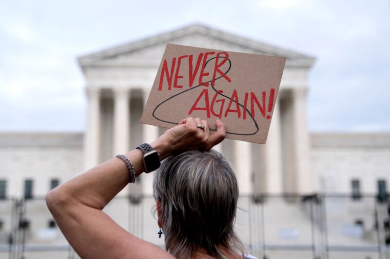 A pro-choice demonstrator holds a sign with a coat hanger and the words 