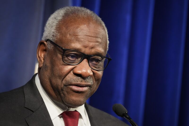 Supreme Court Justice Clarence Thomas speaking into a microphone at an event.