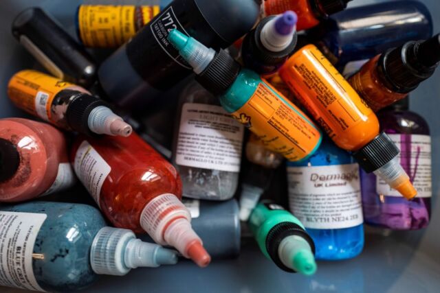 Colored ink bottles jumbled together in a box at a tattoo parlor in Berlin.