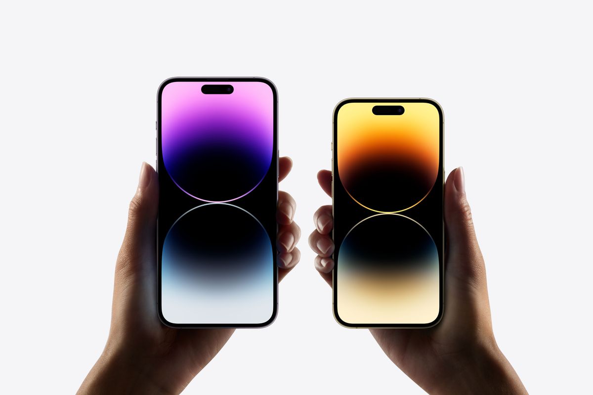 iPhone 14 Pro and iPhone 14 Pro Max being held next to each other, with their displays showing a colorful wallpaper.
