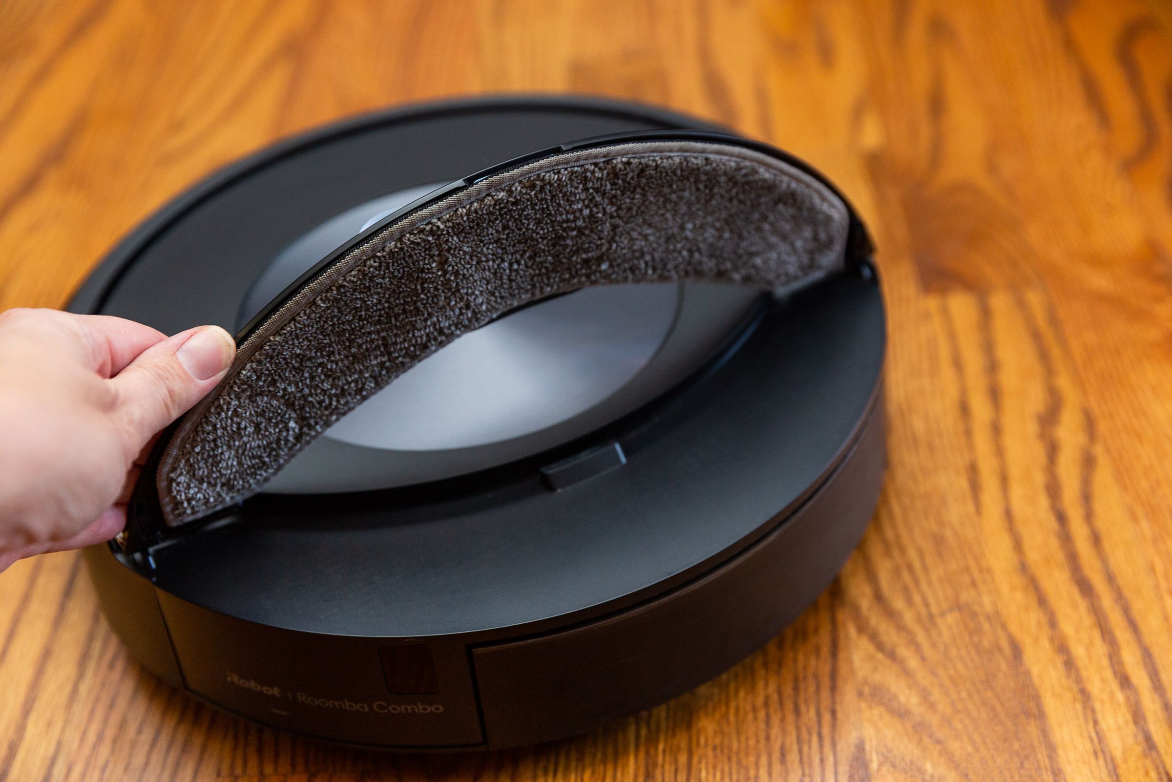 A hand lifting the mopping arm of the Roomba Combo j7 plus to show the mopping pad.