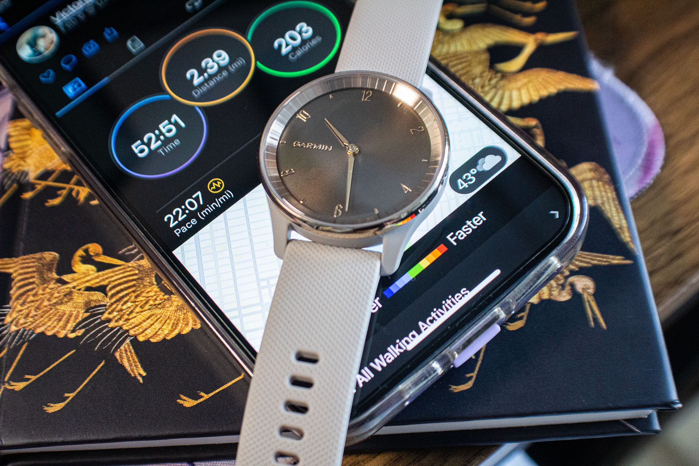The Garmin Vivomove Trend on top of a phone showing Garmin Connect app