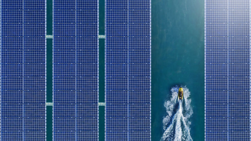 A boat passes by rows of floating solar panels.