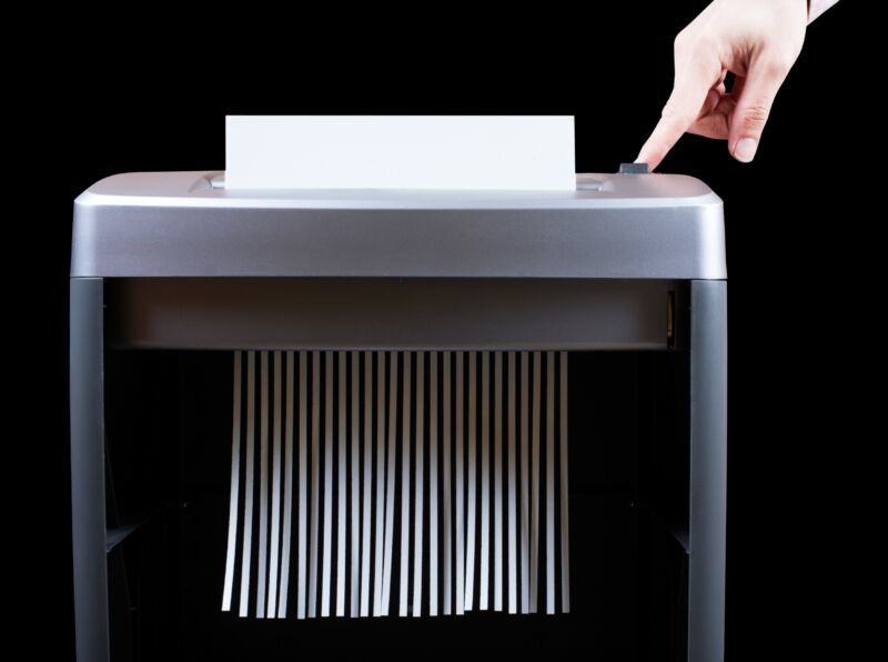 A piece of paper being destroyed in a paper shredder machine.