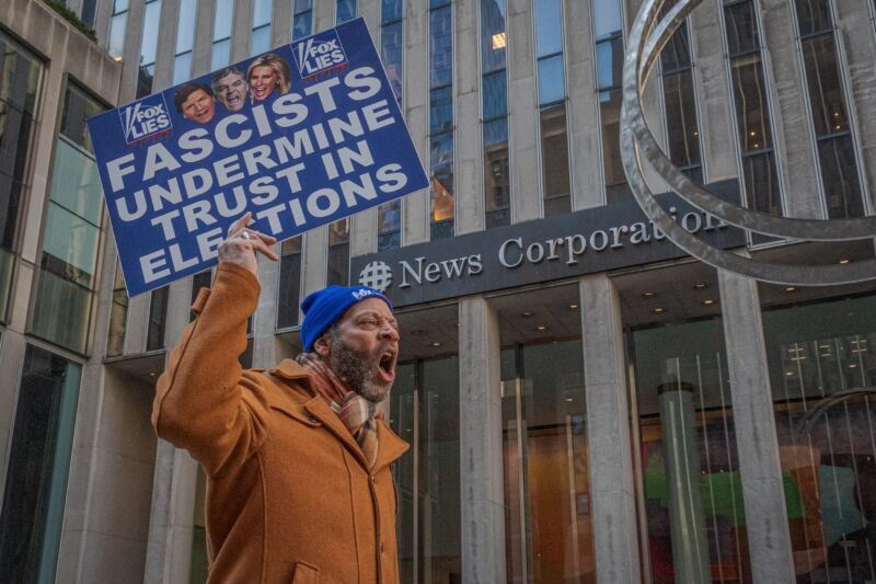 A man holds a sign that says