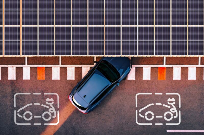 Directly above view taken with drone of a charging station for electric and hybrid cars using solar panels to generate electricity to charge cars battery while are parked in the city.