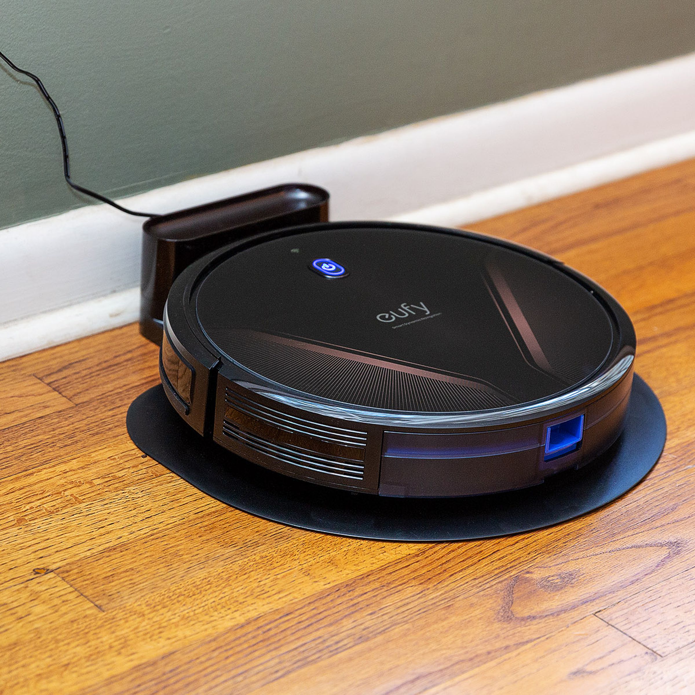 Eufy’s G20 Hybrid plugged into the wall resting on a hardwood floor.