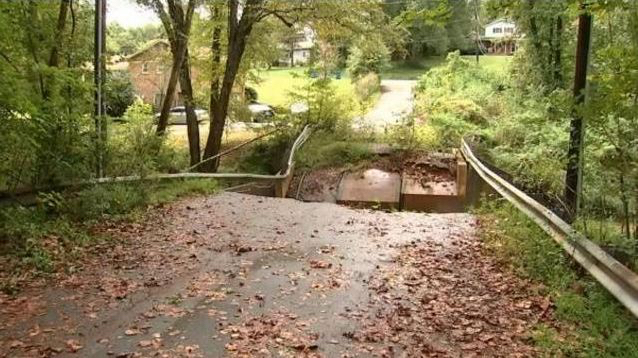 A collapsed bridge on a small road without any lights or barriers to protect drivers.