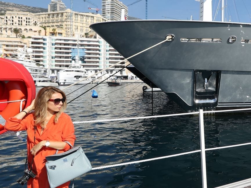 A woman poses in front of a yacht.