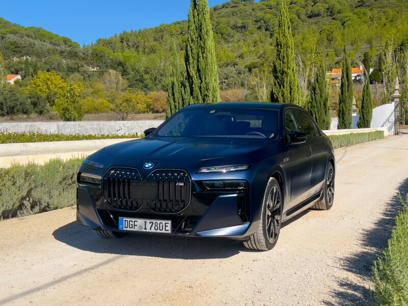 A dark blue BMW i7 seen with some poplar trees in the background