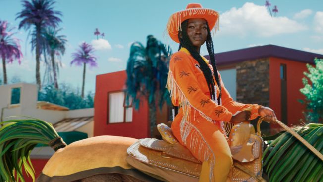 Woman in orange cowgirl suit riding on a horse