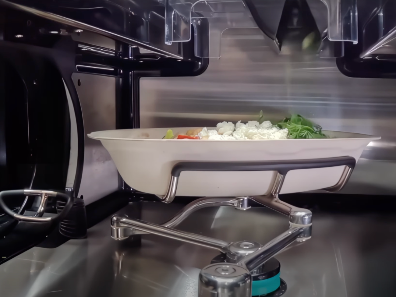 Metal arms move bowls from one pan to another.