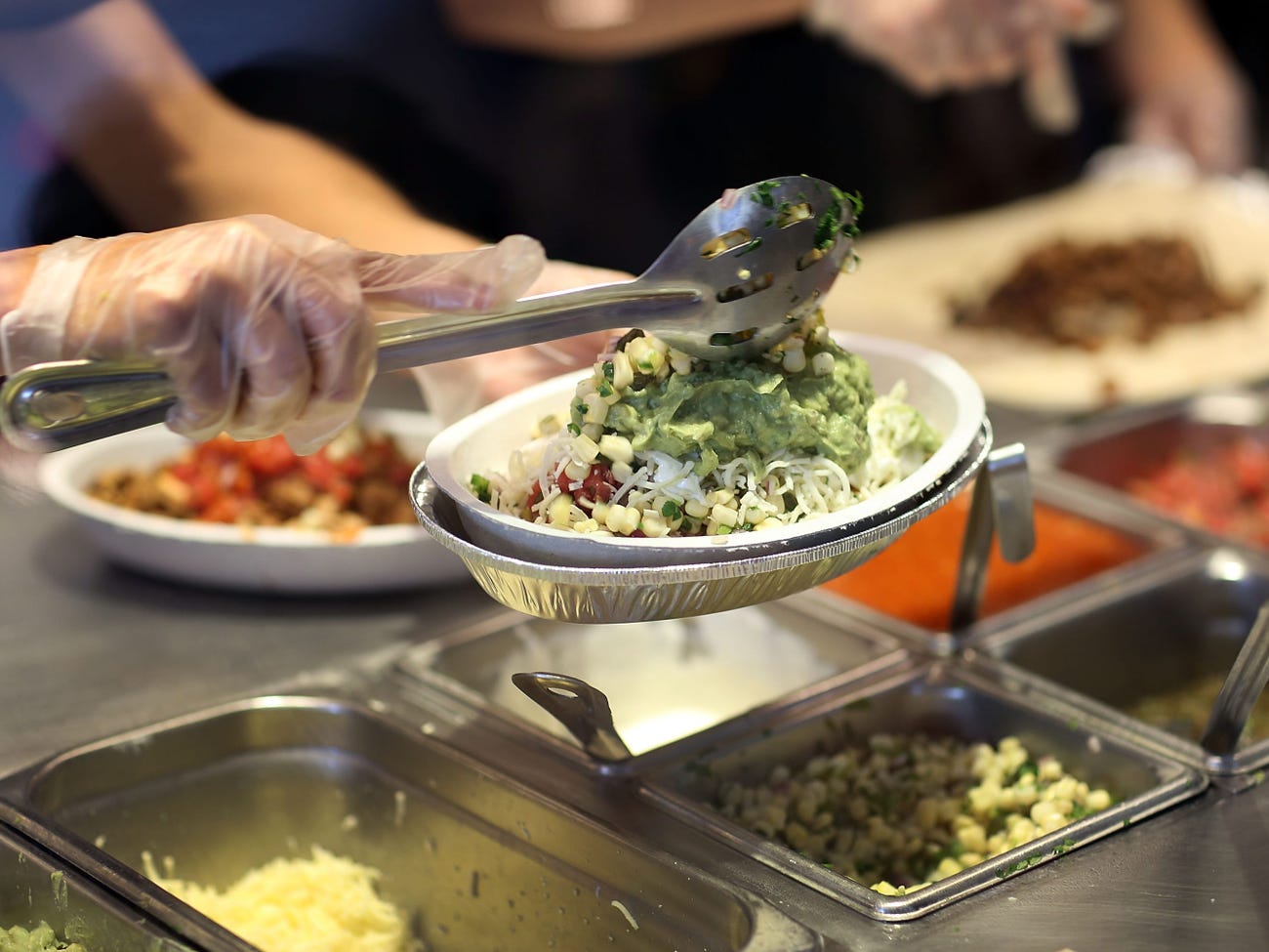 Someone dolloping guacamole on a Chipotle bowl.