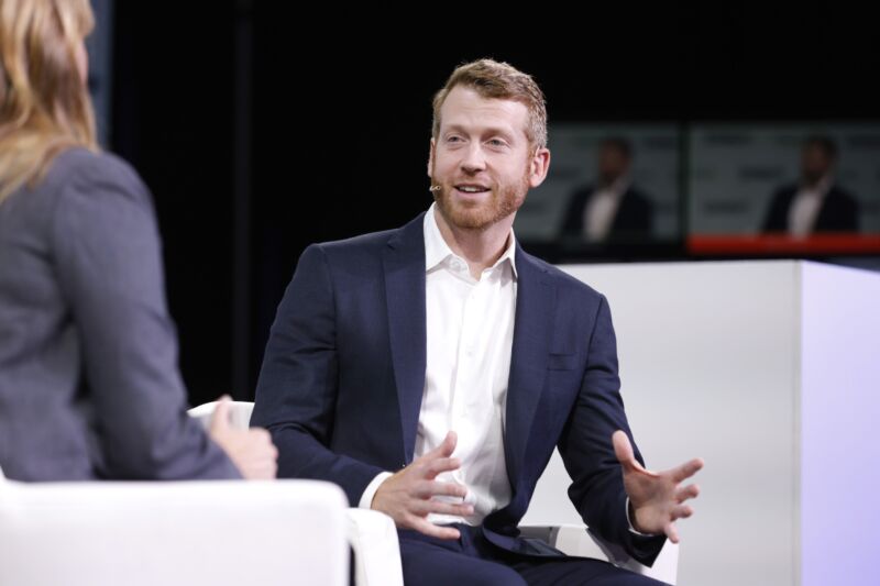 Kyle Vogt speaks while sitting on a stage during an event.