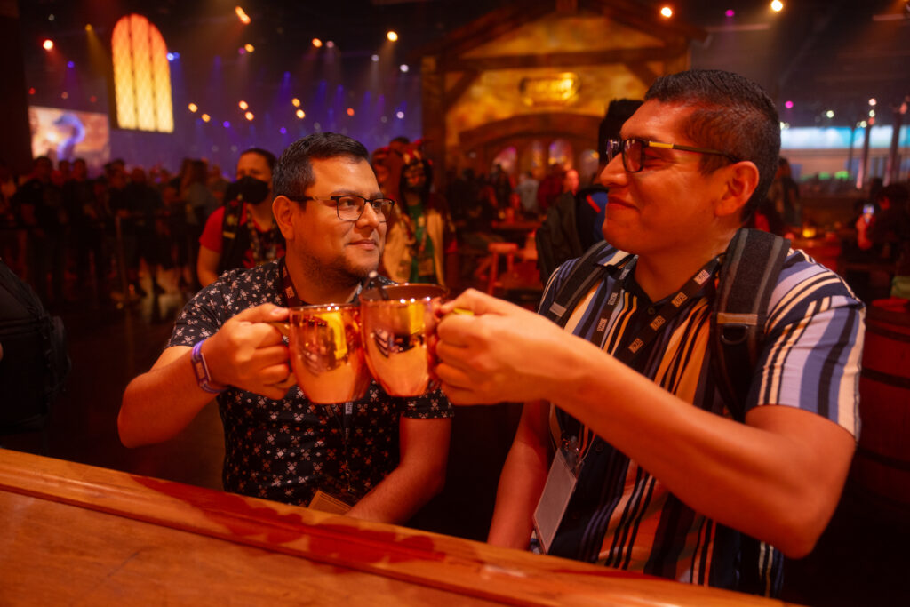 two men sitting at a bar clinking glasses