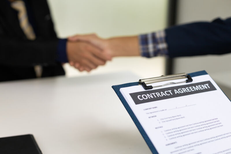 Handshake and contract signing an agreement.